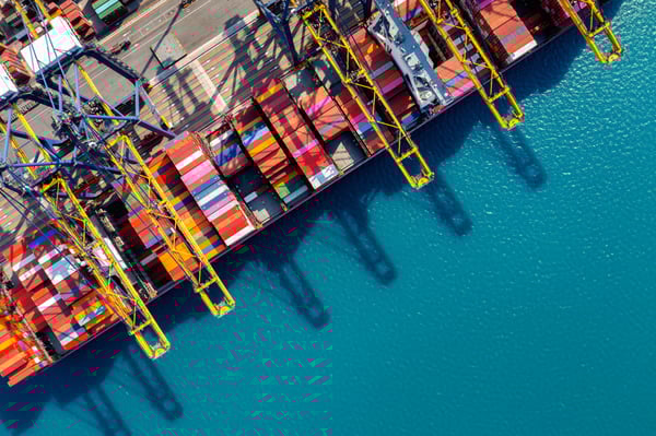 The top view of a ship in a port, filled with colorful containers, representing the question what is logistics