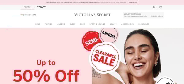 The main page of Victoria's Secret website, with the menu with different products categories from cosmetics to accessories, and the banner announcing clearance, with discounts in various products. The retailer's webpage is in tones of pink, white and black, with the Victoria's Secret logo on the top of the page.